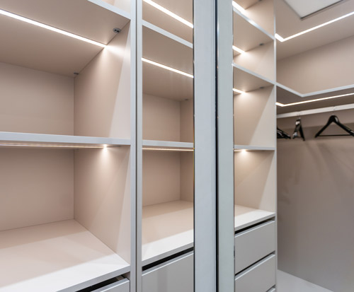 Bespoke fitted wardrobe with shelves and lighting by Bookham Kitchens
