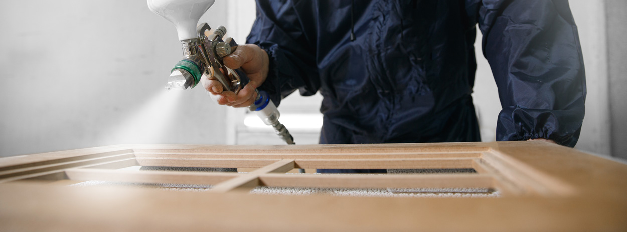 A man spray painting a kitchen cupboard