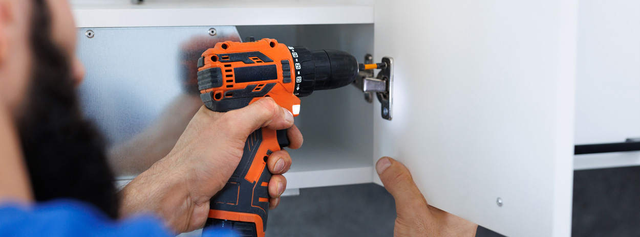 A man replacing a kitchen cupboard door