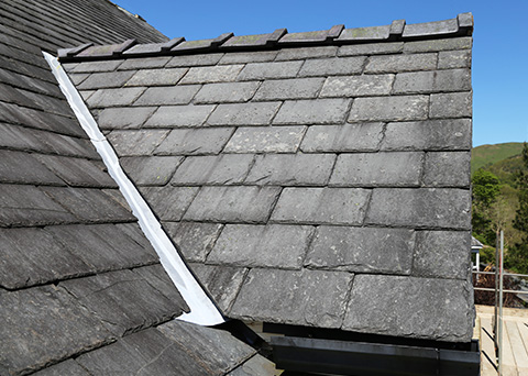 slate roof shingles on a house showing a seamless finish with clear blue sky 10 tips for roof maintenance