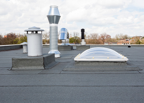 roof with various ventilation systems and skylights for natural light and energy efficiency including two metal vents and a plastic dome skylight