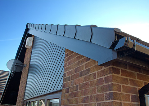 roof edge with decorative tiles and a metal gutter system on a brick house featuring a clear blue sky as background six roof design elements