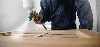 A person respraying a kitchen cabinet
